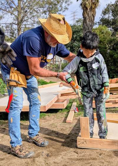 A volunteer helping a boy drive a screw