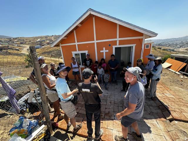 Volunteers and family at an orange home with a cross
